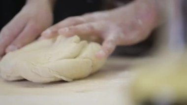 Fırıncı hamur yoğurdunu ahşap yüzeye döker. yakın plan