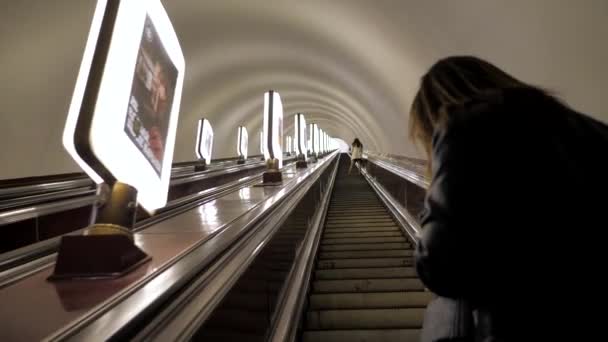 La chica mira el teléfono y sube por la escalera mecánica en el metro — Vídeos de Stock
