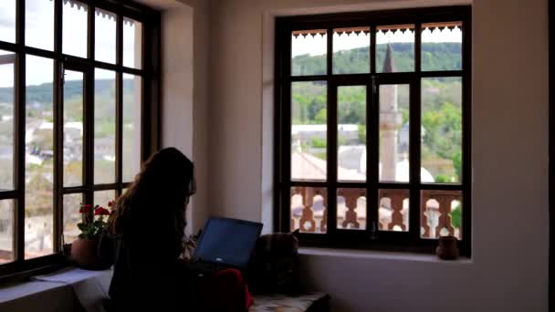 Ένα νεαρό κορίτσι εργάζεται σε ένα φορητό υπολογιστή σε ένα ανατολίτικο στυλ — Αρχείο Βίντεο