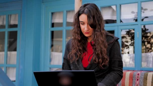 イーストスタイルのパティオでラップトップで働いている若い女の子 — ストック動画