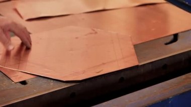 Usta kesiciyi kullanarak ürünün şeklini bir bakır tabakasından kesiyor.