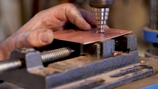 Mästaren med hjälp av en fräsmaskin gör ett hål på en bit koppar — Stockvideo