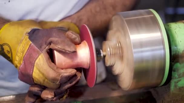 The master polishes the edges of the product on the polishing disc. copper cezve — 비디오