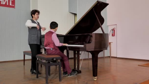 Il ragazzo suona il pianoforte, l'insegnante mostra come eseguire correttamente la composizione — Video Stock