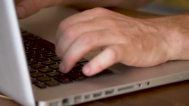 Dizüstü bilgisayarda çalışan adam, elleri klavyede yakın plan baskı yapıyor.