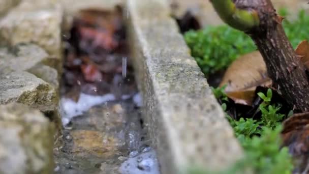 In einem gemütlichen Wohnhof fließt Schmelzwasser in den Graben — Stockvideo