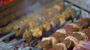The young man is grilling on the coals the pieces of meat