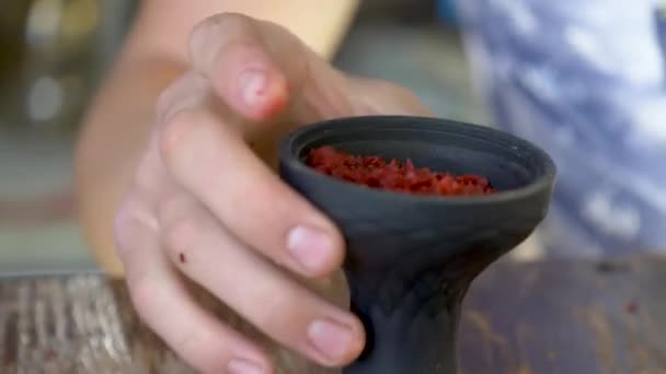 A young man lays fragrant tobacco in a hookah. bowl for shisha — 비디오