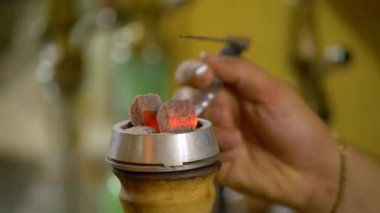 The young man is preparing a hookah. Lifted the bowl with coals.