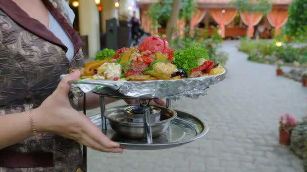 The waiter delivers to the table cooked in a cauldron vegetables. — Stockvideo