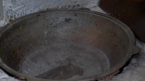 У чавунному кодоні воду заливають з глиняного глечика, щоб помити її — стокове відео