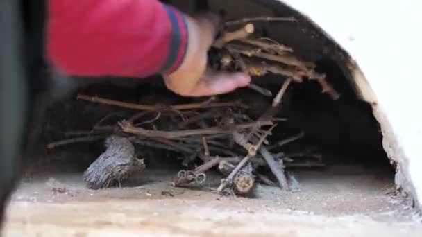 Le cuisinier met du bois de chauffage dans le pour allumer un feu dans la pierre de foyer — Video