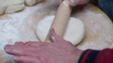 Ortaçağ fırınında ekmek pişirmek için hamuru merdaneyle saran adam.. 