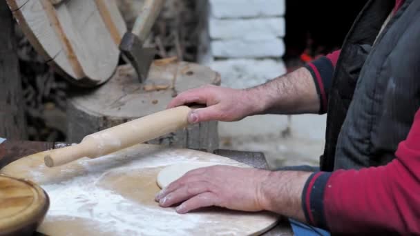 사람 이 중세기 화덕에서 납작 한 빵을 굽기 위한 압착 핀을 가지고 반죽을 굴린다. — 비디오