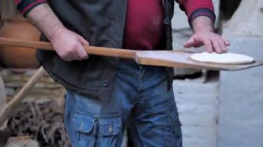 Adam çiğ ekmeği ahşap bir spatulaya koydu ve fırına koydu..