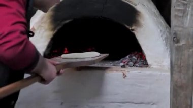 Adam çiğ ekmeği ahşap bir spatulaya koydu ve fırına koydu..