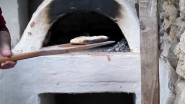 Fırıncı fırından ahşap bir spatulayla fırından fırınlanmış yassı ekmeği çıkardı.