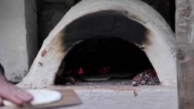 Adam çiğ ekmeği ahşap bir spatulaya koydu ve fırına koydu..