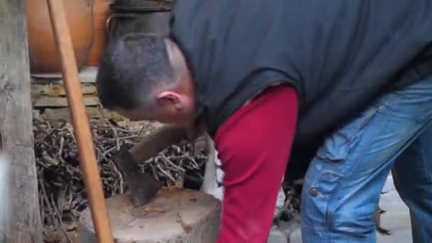 Um homem está cortando madeira com um machado, para acender uma casa lareira — Vídeo de Stock