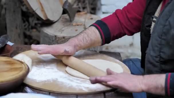 Az ember sodorja a tésztát egy sodrófával, hogy kenyeret süssön a középkori sütőben. — Stock videók
