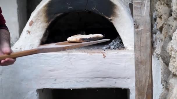 Fırıncı fırından ahşap bir spatulayla fırından fırınlanmış yassı ekmeği çıkardı. — Stok video