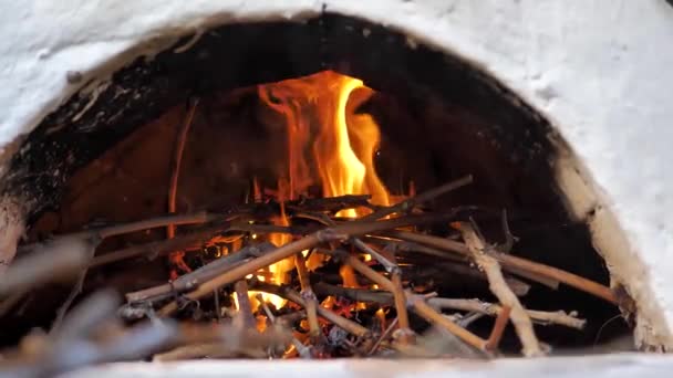 Чоловік розтопив середньовічну плиту, поставивши дрова, щоб пекти хліб . — стокове відео