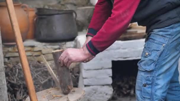 Bir adam ev ocağını yakmak için baltayla odun kesiyor. — Stok video