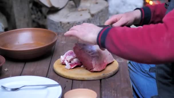 Повар на деревянной доске режет мясо на куски, чтобы поджарить его. — стоковое видео