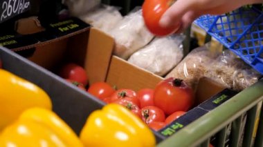 Dükkanda satıcı tezgahın üzerine kırmızı domates koyar.