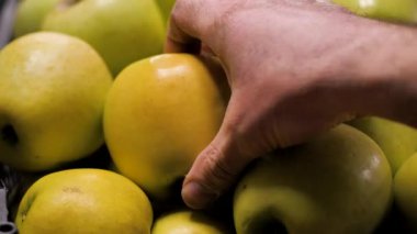 Müşteri tezgahtan yeşil elmaları arabaya götürür.