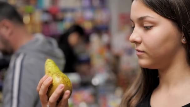 Una giovane ragazza seleziona accuratamente le pere in un cesto dal bancone — Video Stock