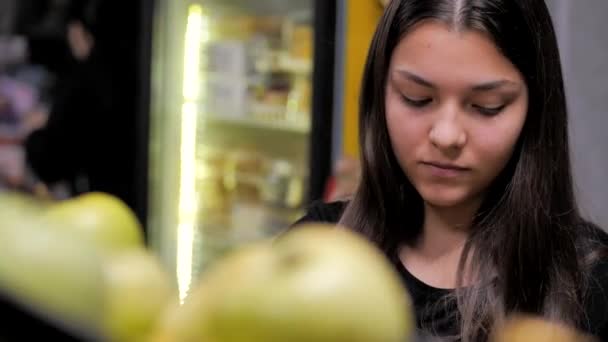 Mladá dívka sbírá zelená jablka do košíku z pultu — Stock video