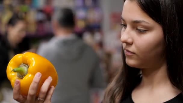 Das junge Mädchen pflückt eine gelbe Paprika vom Tresen — Stockvideo