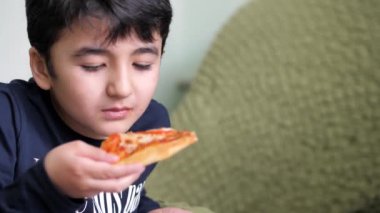 Siyah saçlı çocuk pizza yiyor Margarita.