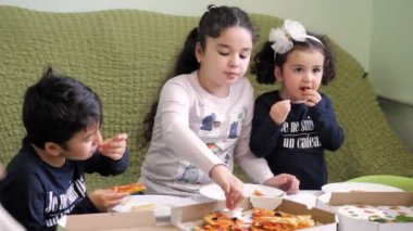 Pizza siparişi. Oğlan ve iki kız pizza ve patates kızartması yiyorlar.