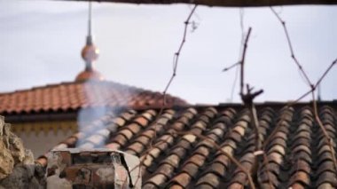 Ortaçağ şöminesinin üstündeki kiremitli çatı baca dumanından geliyor.