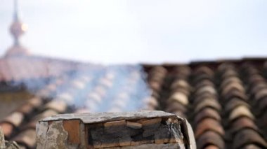 Ortaçağ şöminesinin üstündeki kiremitli çatı baca dumanından geliyor.