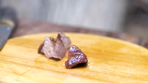 O cozinheiro coloca a carne acabada em uma tábua de madeira. polvilhe com sal — Vídeo de Stock