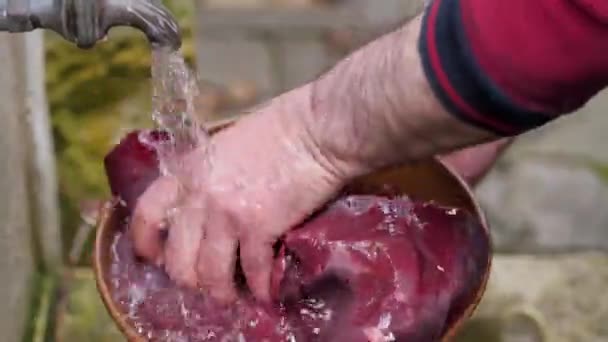 The cook washes the beef liver under the tap in the yard — Stock Video