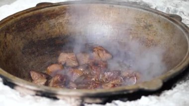 Et parçaları (karaciğer) açık ateşte demir bir tencerede yağda kızartılır.