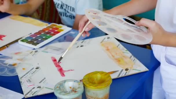 La ragazza impara a dipingere con vernici ad acquerello. disegna un arco rosso — Video Stock