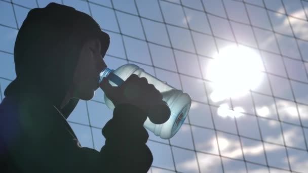 Jonge sportman drinkt water uit fles na training — Stockvideo