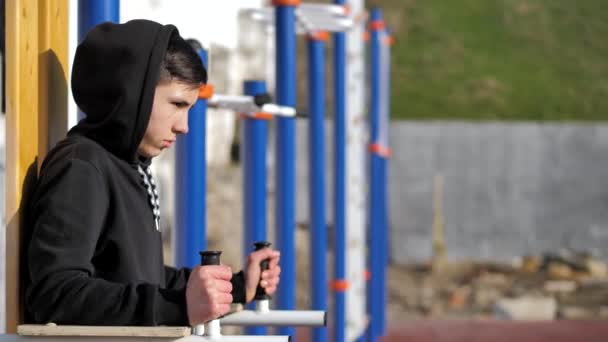 Street work out. a young guy in a hoodie makes a warm-up. fitness — Stock Video