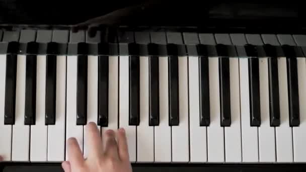 Fille joue du piano. mains en gros plan. la clé du piano. vue de dessus — Video