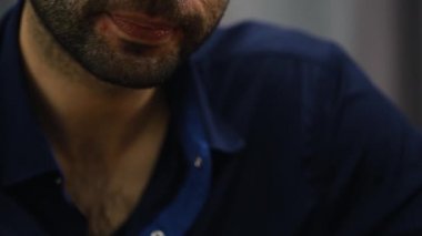 A man with a beard sitting in the room says something and Smoking a cigar