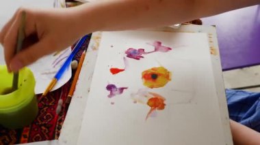 Little girl learns to paint with watercolor paints. draws flowers