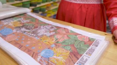 Mağazadaki kadın işlemek için boncuklu bir resim seçiyor. yaratıcılık dükkanı