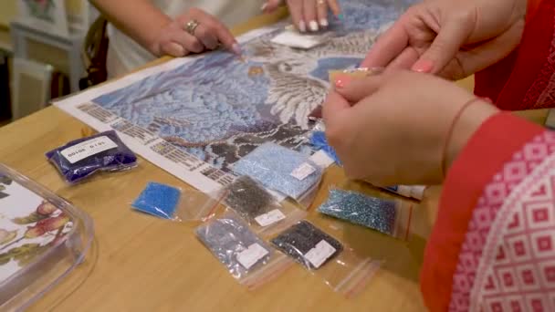 La mujer con el vendedor escogen los colores de las cuentas para el bordado. tienda de creatividad — Vídeos de Stock