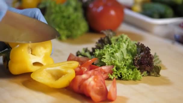 In de keuken van het restaurant snijdt de man een paprika voor salade. — Stockvideo