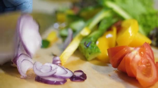 En la cocina del restaurante el hombre corta la cebolla para una ensalada . — Vídeo de stock